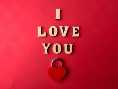 Aşk kilidi ve ahşap harfler kırmızı bir arka planda 