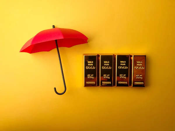 Sarı Arka Planda Kırmızı Şemsiye Kaplanmış Altın Külçesi — Stok fotoğraf