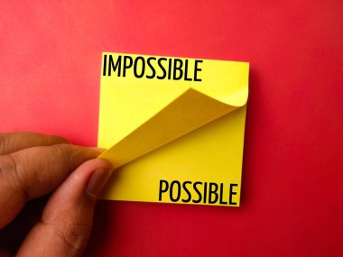 Sticky note with the word IMPOSSIBLE POSSIBLE on a red background clipart