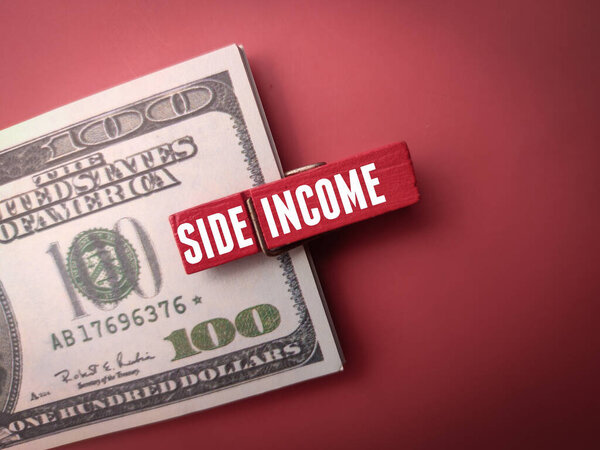Banknotes and wooden clips with word SIDE INCOME on a red background