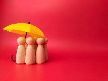 Bir grup tahta bebek sarı bir şemsiye altında saklanıyor, tahta mandal bebeklerini koruyor, planlıyor, aileleri kurtarıyor, riskleri ve krizleri, sağlık hizmetleri ve sigorta kavramlarını engelliyor..