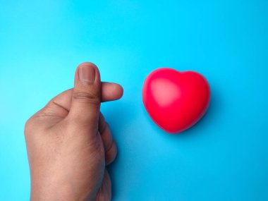 Kırmızı kalp şekli, mavi arka planda birinin elinden çıkan küçük bir aşk. Kalp kontrolü ya da aşk konsepti için kullanılabilir