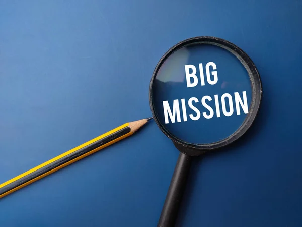 Magnifying glass and pencil with the BIG MISSION on a blue background