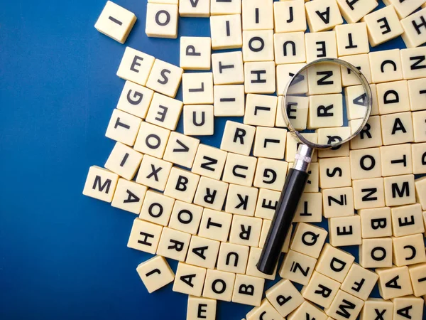 stock image Closeup magnifying glass and toys letters on a blue background
