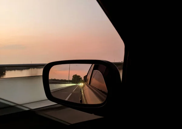 車の窓から日の出と車のサイドミラーに日の出の光を見て — ストック写真