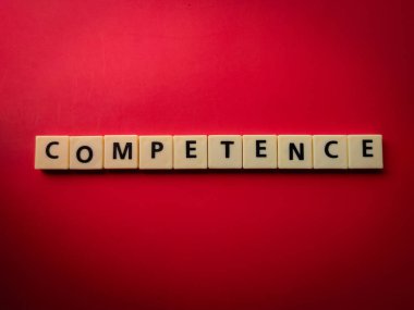 Kırmızı arkaplanda COMPETENCE sözcüğüyle en üstteki oyuncak harfleri