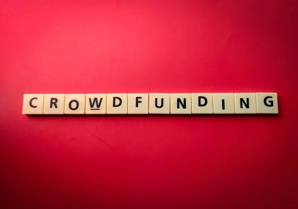 stock image Top view toys letters with the word CROWDFUNDING on a red background