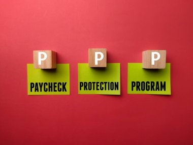Kırmızı zemin üzerinde PPP, PAYCHECK PROTECTION PROGRAM yazan renkli yapışkan not ve tahta küp