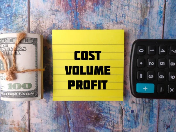 木制背景上印有 Cost Volume Profit 字样的薄薄的钞票和钞票 — 图库照片