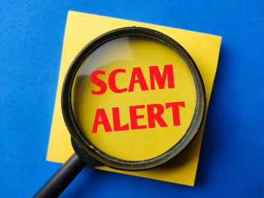 Magnifying glass with the word SCAM ALERT on a blue background