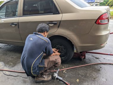 Pantai Remis, Perak, 19 Temmuz 2023: Lastik atölyesinde çalışan bir işçi bir aracın arka lastiğini söküyor