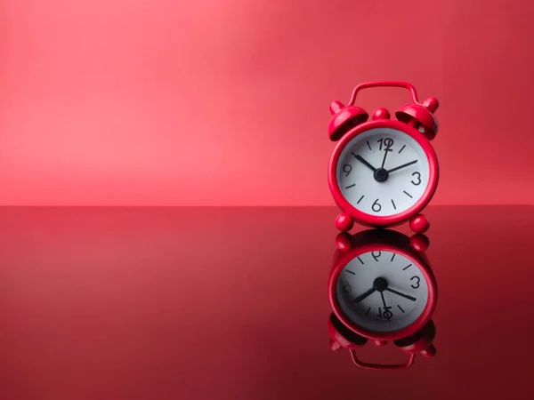 Red alarm clock with reflection on a red background. Copy and text space.