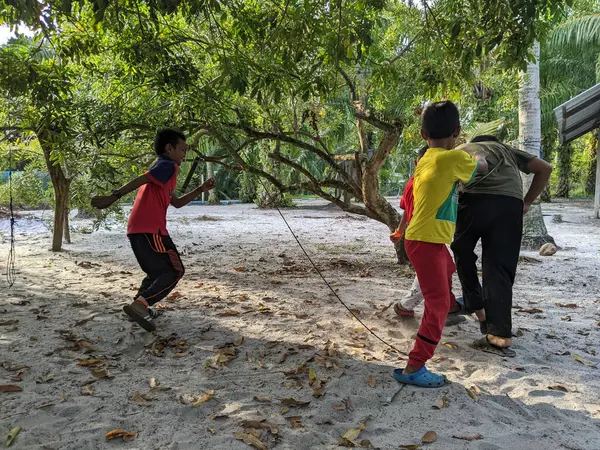 Perak, Malezya, 30 Temmuz 2023: Bir çocuk akşam bahçelerinde bir ağacın altında futbol oynuyor.