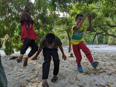 Perak, Malezya, 30 Temmuz 2023: Bir çocuk bir gol attıktan sonra ünlü futbolcu stili yaparken bir ağacın altında futbol oynuyor.