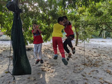 Perak, Malezya, 30 Temmuz 2023: Bir çocuk bir gol attıktan sonra ünlü futbolcu stili yaparken bir ağacın altında futbol oynuyor.