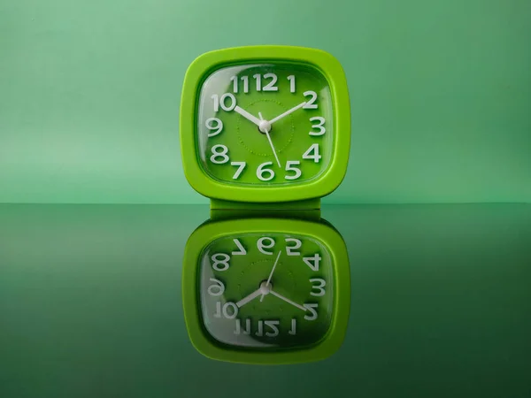 Grüne Uhr Auf Grünem Hintergrund Mit Reflexion Auf Schwarzer Acrylplatte — Stockfoto
