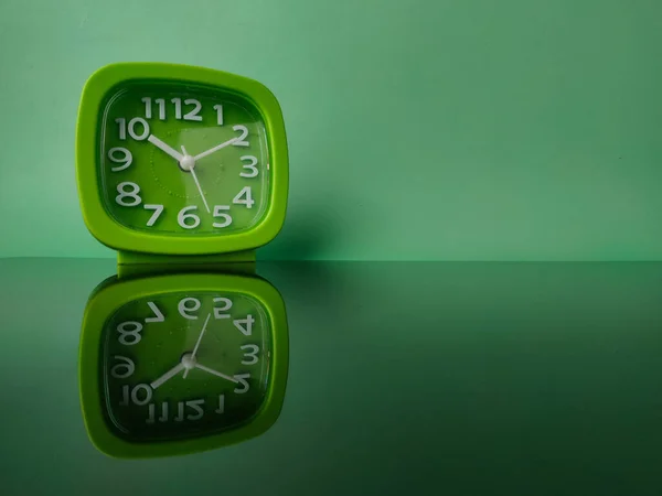 Grüne Uhr Auf Grünem Hintergrund Mit Reflexion Auf Einer Schwarzen — Stockfoto