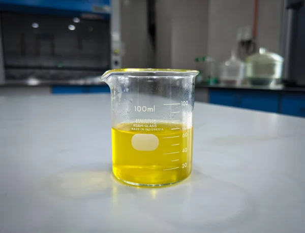 The yellow oil and chemical liquid that had been mixed in a beaker were on the table of a laboratory in a factory