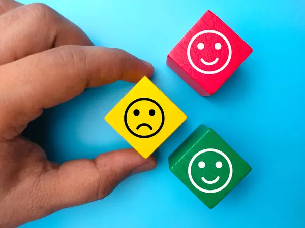 Hand holding colored wooden cube with expression unhappy and happy. Positive and negative person concept.