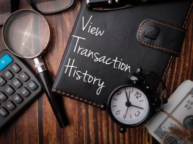 Top view magnifying glass,banknotes and calculator with the word View Transaction History. clipart