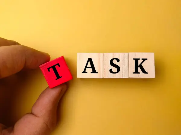 stock image Hand holding colored wooden cube with the word TASK