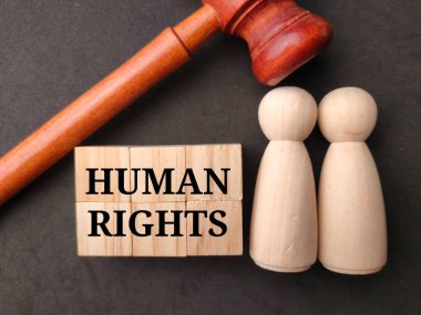 Gavel ve ahşap figürler. Siyah arka planda insan hakları var..