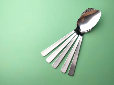 Yeşil arka planda paslanmaz çelik kaşık..