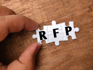 Tahta arka planda RFP sözcüğüyle el ele tutuşan beyaz bulmaca.