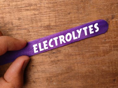 Elde dondurma çubukları ile ahşap arka planda ELECTROLYTES metin.
