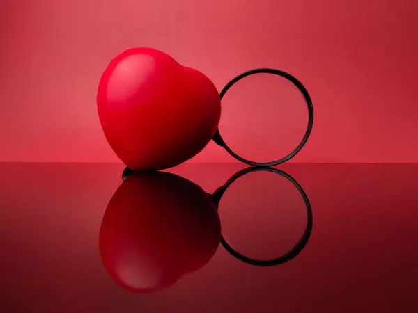Red love and magnifying glass with reflection on a red acrylic board