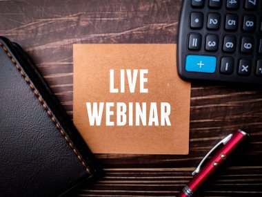 Tahta zemin üzerinde LIVE WEBINAR metin ile Not Defteri, kalem ve hesap makinesi.