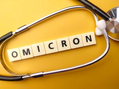 Üst görünüm steteskop ve oyuncaklar kelime sarı arka planda OMICRON metin.