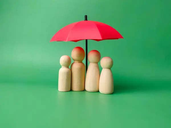 A wooden peg doll family cover by red umbrella on a green background