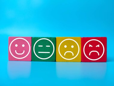 Mavi arkaplanda emoji sembolü olan renkli ahşap blok. Müşteri inceleme kavramı.