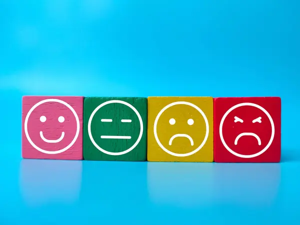 蓝色背景上有情感符号的彩色木块 顾客评审概念 免版税图库照片