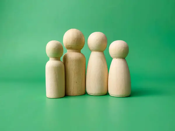 A wooden peg doll family on a green background. The family concept.