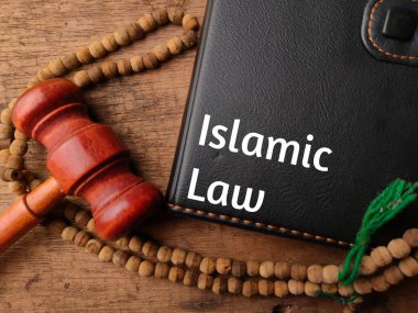 Üst görünüm dua boncuğu, tokmak ve tahta zemin üzerinde İslam hukuku yazılı not defteri.