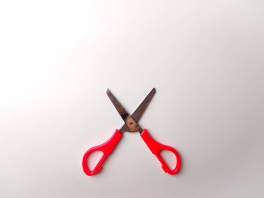 Üst görünüm kırmızı makas ortada beyaz arkaplan üzerinde.