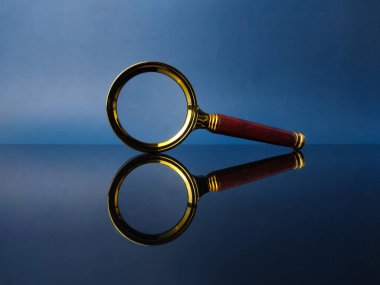 Mavi arka planlı siyah akrilik bir tahtada yansıma klasik büyüteç.