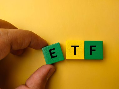 Sarı arka planda ETF yazılı renkli ahşap el ele tutuşmalar..