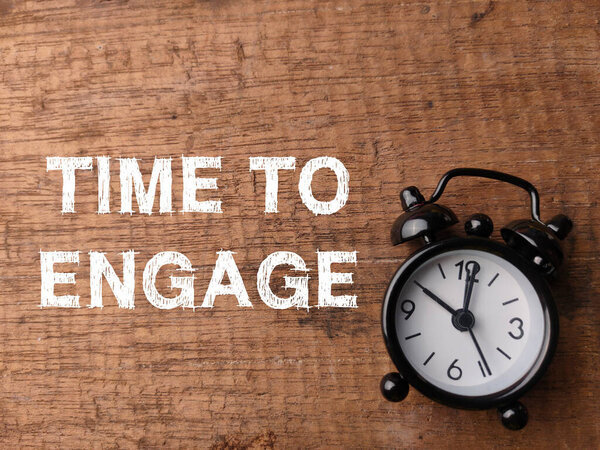 Топ-часы и текст TIME TO ENGAGE на деревянном фоне.