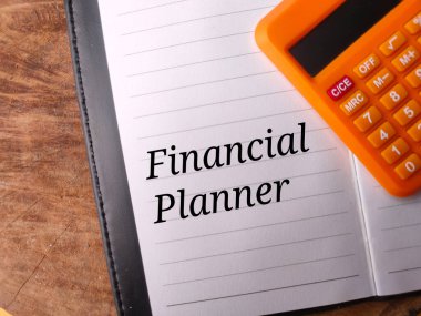 Tahta zemin üzerinde metin Finansal Planlayıcı olan üst görünüm hesap makinesi ve defter.