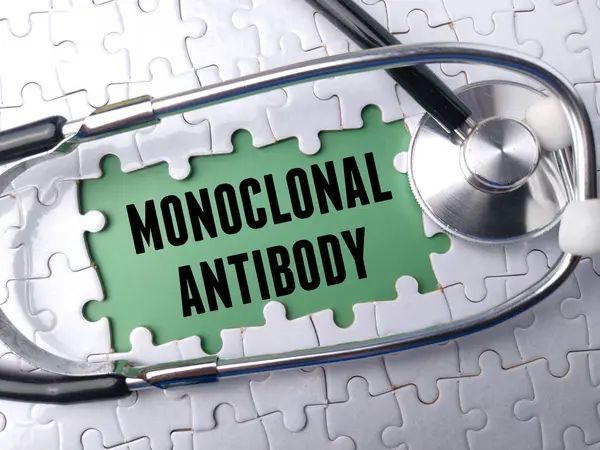 白色拼图背景上带有文本Monoclose Nal Antibody的顶视图听诊器 图库照片