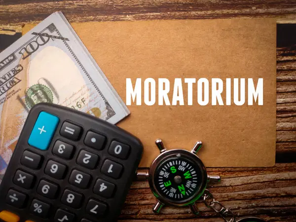 stock image Top view calculator,compass and banknotes with text MORATORIUM on wooden background.
