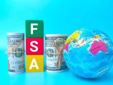 Dünya küresi ve banknotları mavi arka planda FSA sözcüğüyle.