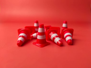 Kırmızı arka plana saçılmış küçük kırmızı plastik koniler..