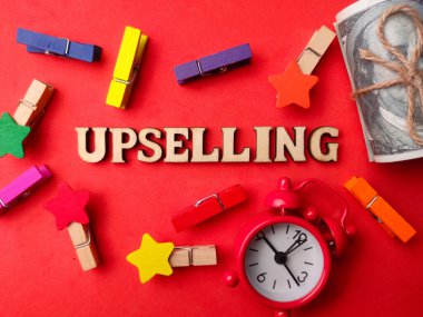 Üst görünüm banknotları, saat, tahta klipler ve kırmızı arkaplanda yazı olan ahşap sözcük.