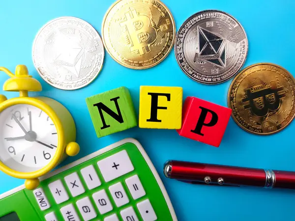 stock image Clock,pen,calculator,golden bitcoin, silver ethereum and colored cube with text NFP on blue background.