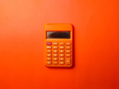 Turuncu arkaplanda üst görünüm turuncu hesap makinesi.
