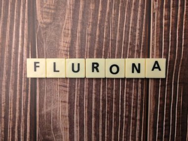 Top view toys latters with word FLURONA on wooden table. Flurona, double infection of Covid and Flu. clipart